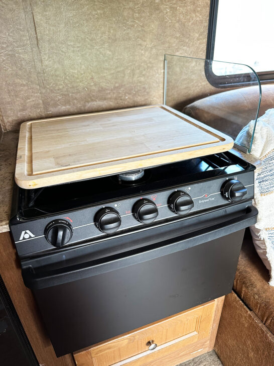 rv stove with cutting board on top of it