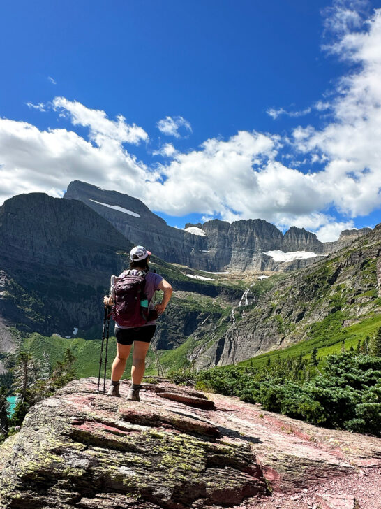 glacier national park and Banff itinerary woman standing on large rock with mountains in distance