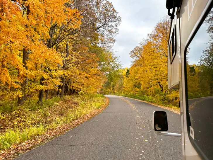 view of road with yellow trees and front of motorhome beginning rving