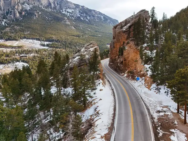 aerial view of the peak to peak highway in colorado with snowy mountainside with road carved through it