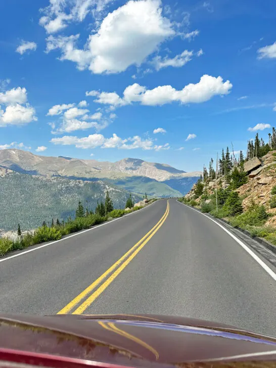 view of a road with mountains with clouds in the sky