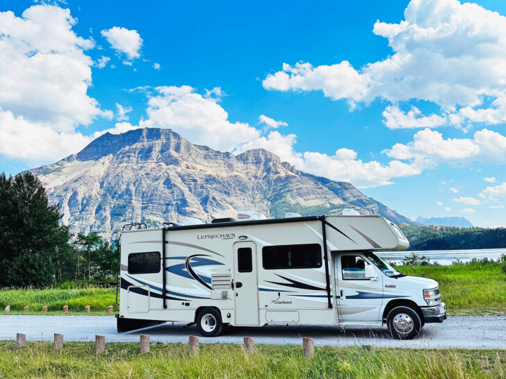RV camping for beginners view of motorhome with tan and stripes on road with large mountain behind