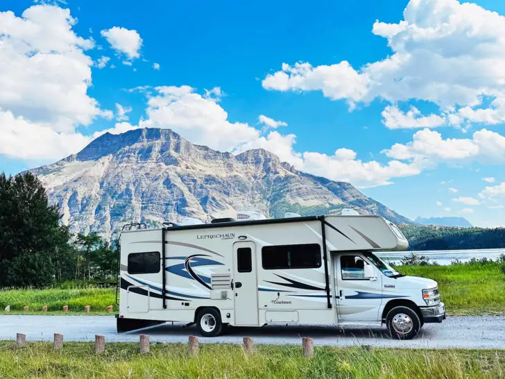 RV camping for beginners view of motorhome with tan and stripes on road with large mountain behind